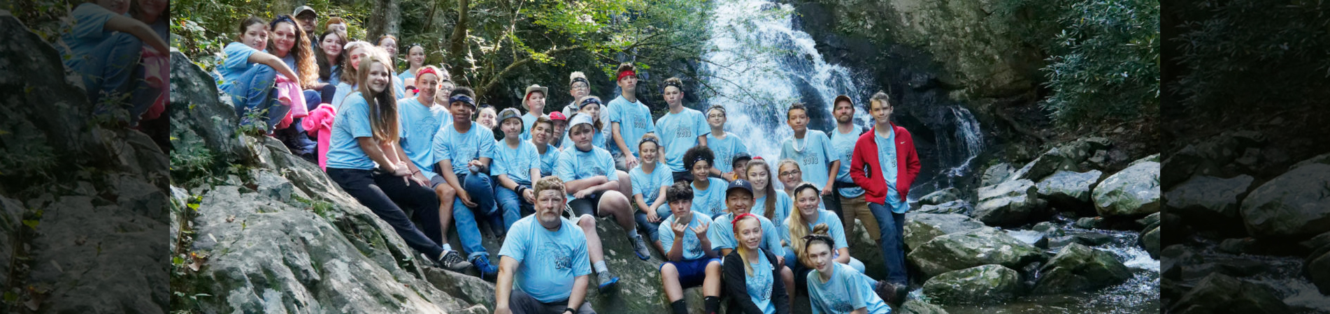 PCS Middle School Class sitting on rocks in front of waterfall at a field trip